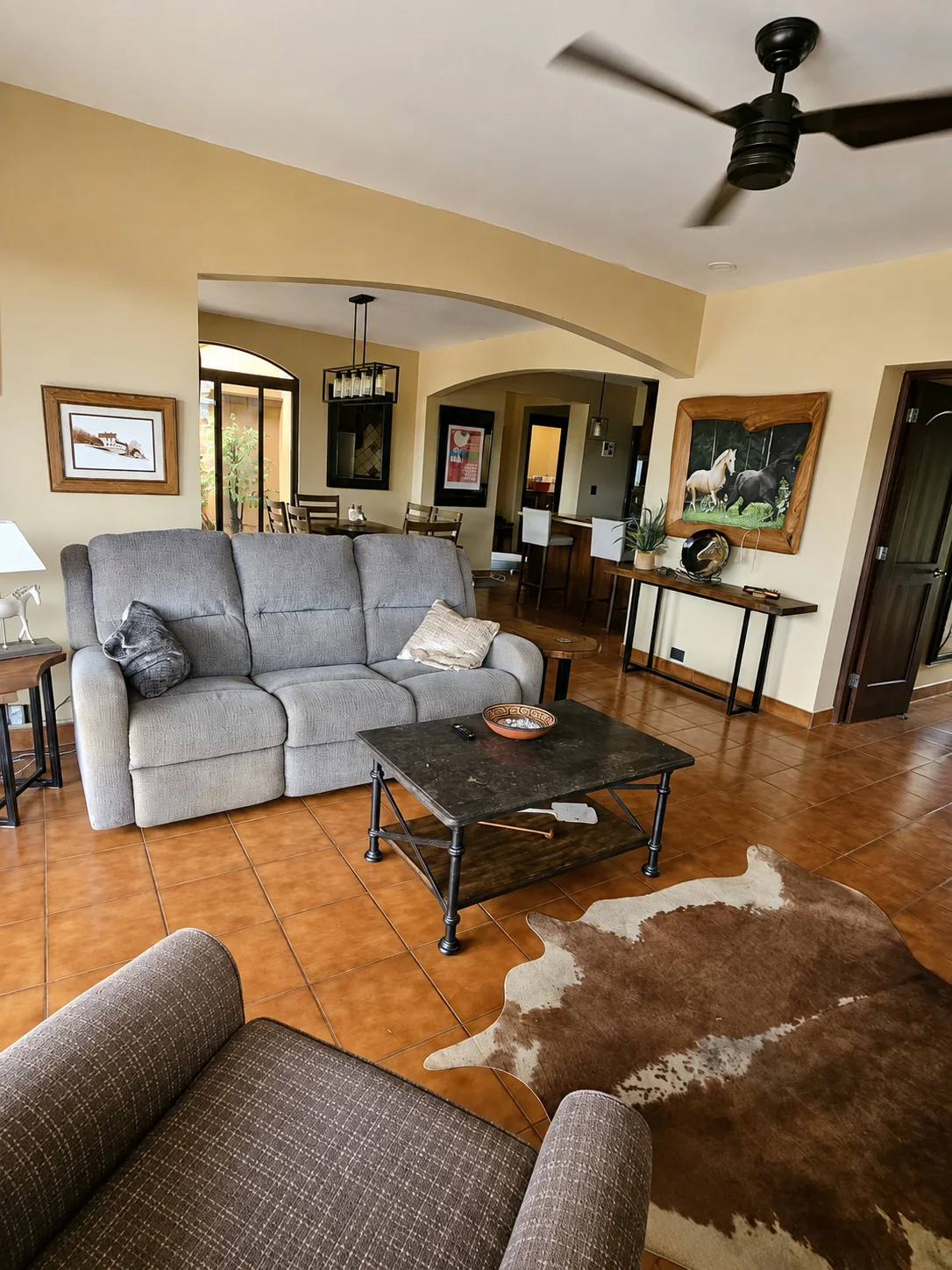 Living room with terracotta floors and arched openings to the dining room